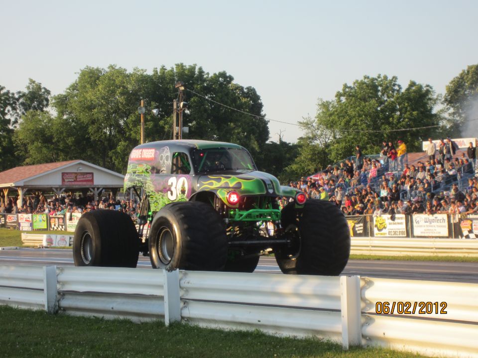Monster truck with flames and number 30 on it, driving past a crowd