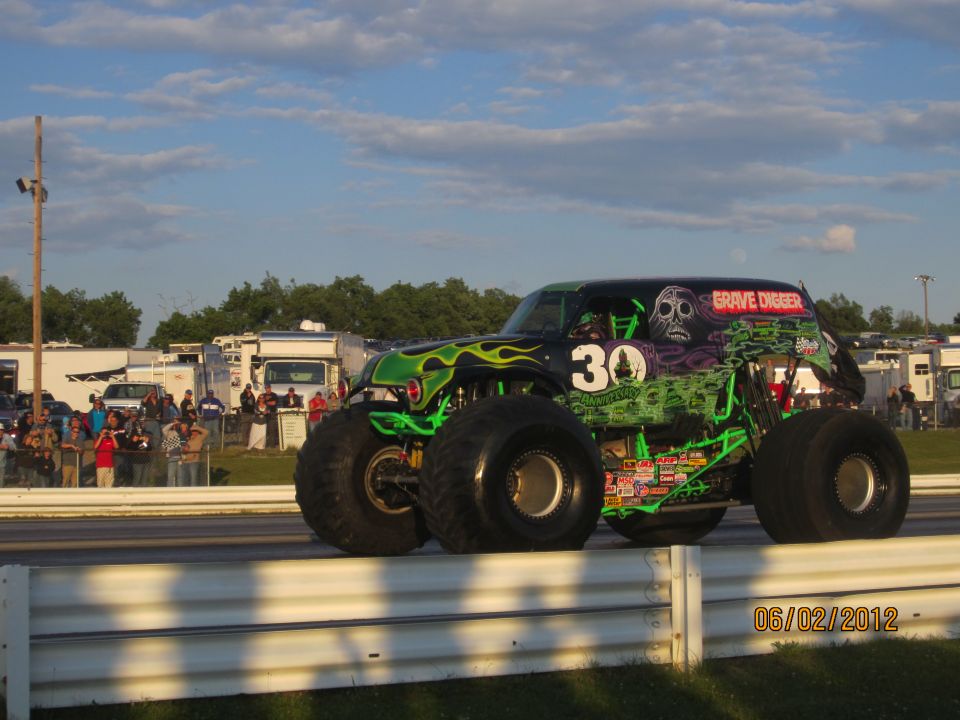 Monster truck with 'Grave Digger' and '30' graphics, black with green flames, on a track