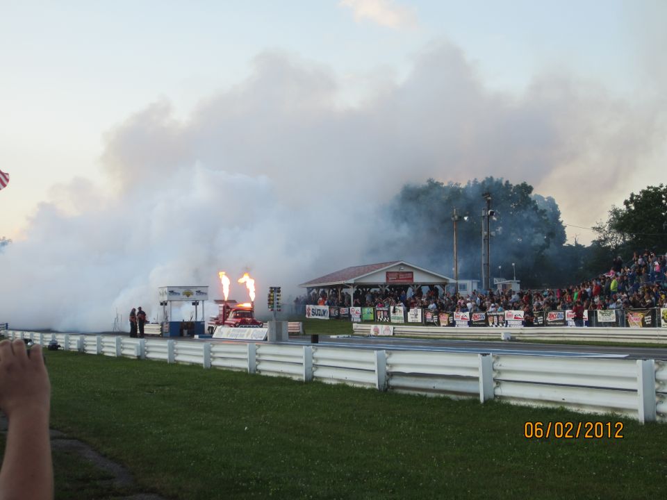 Dragster with flames shooting from exhaust at a race track