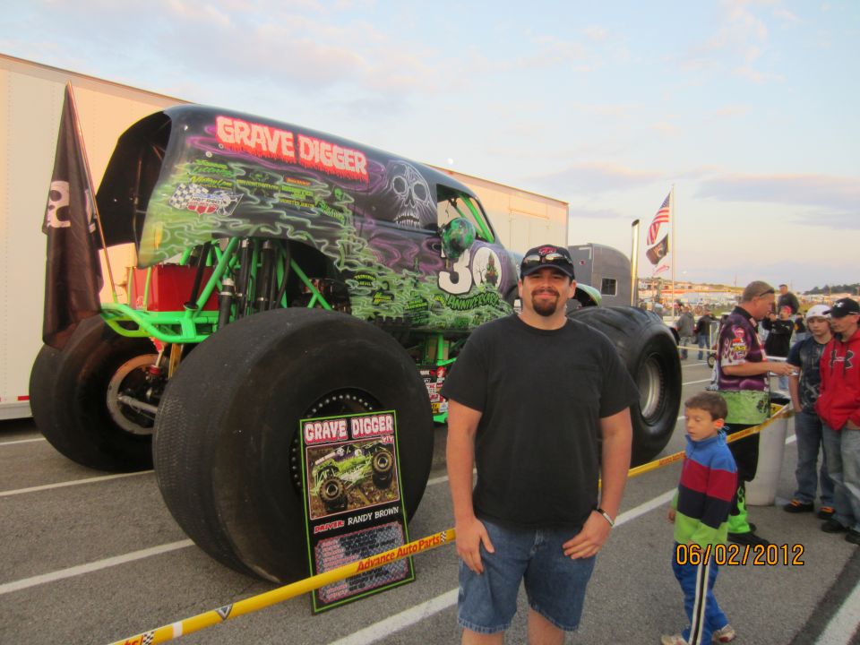 Man standing next to Grave Digger monster truck with '30' on the side