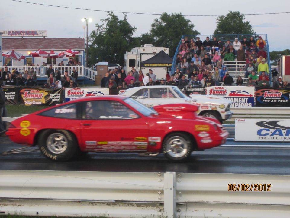Red drag car with racing decals on track, side view