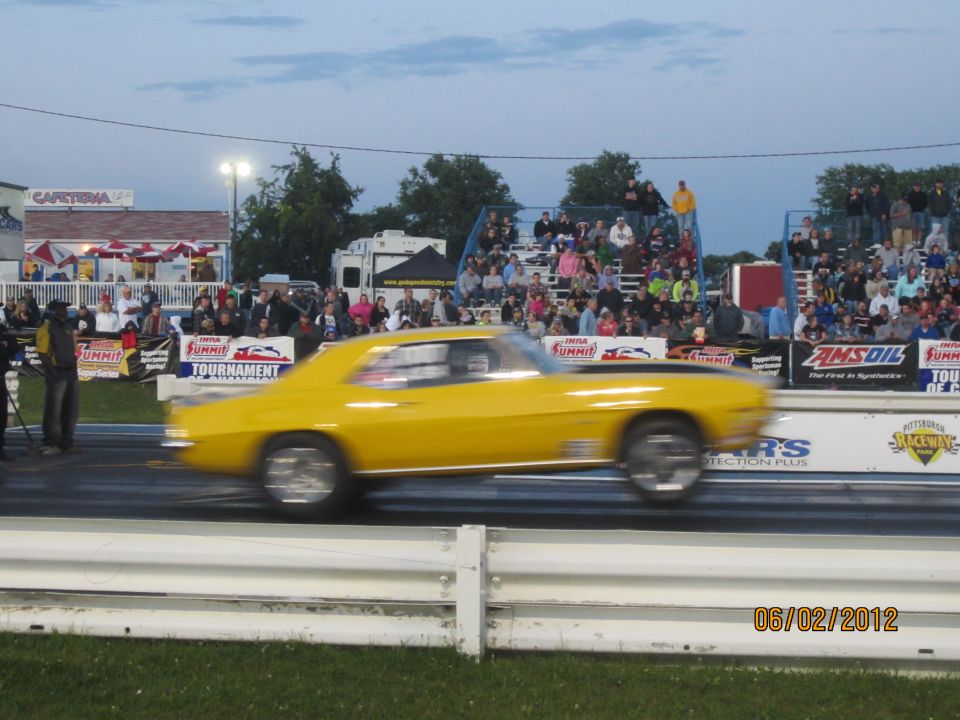Yellow 1969 Chevrolet Camaro drag racing, blurred motion, crowd in background, date stamp 06/02/2012