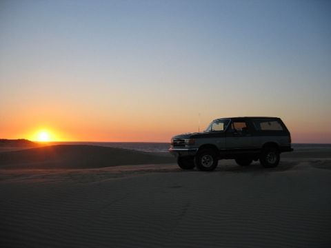 1989 Ford Bronco - Ford Bronco parked on sand dunes during sunset.