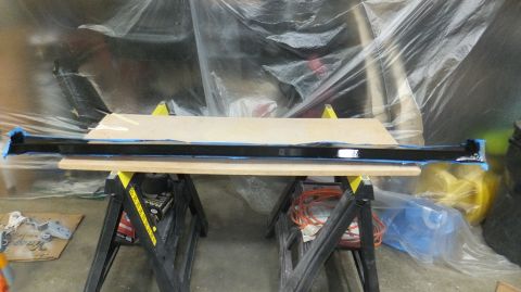 1983 Ford Bronco - A bumper is being worked on, supported by sawhorses in a workshop.