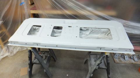 1983 Ford Bronco - A white tailgate, likely for a truck or SUV, is prepped for painting in a workshop.