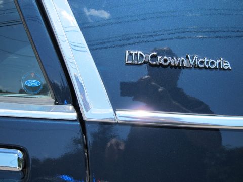 1991 Ford LTD Crown Victoria - close-up of a dark blue car's rear quarter showing the chrome script badge reading LTD Crown Victoria and a Ford oval emblem.