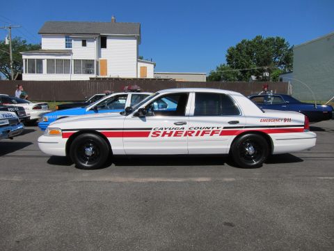1991 Ford LTD Crown Victoria - white Ford Crown Victoria lettered Cayuga County Sheriff with a red stripe and Emergency 911 sits in profile on a residential street with o…