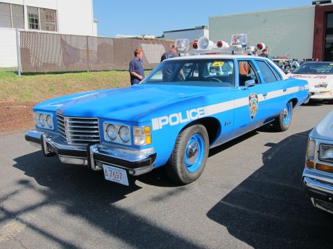 1991 Ford LTD Crown Victoria - blue 'Police' Pontiac sedan with twin round roof lights and white lettering parked at an outdoor classic-car gathering.