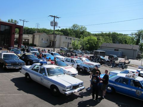 1991 Ford LTD Crown Victoria - Elevated view of a lot packed with police cars, motorcycles, and people at an outdoor public-safety vehicle gathering.
