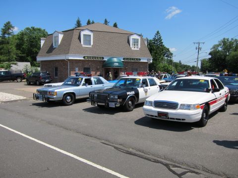 1991 Ford LTD Crown Victoria - row of police cars, white and black sedans, parked in front of the Modugno Electric building.