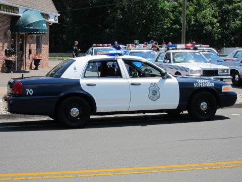 1991 Ford LTD Crown Victoria - blue-and-white Traffic Supervisor police cruiser marked 70 parked along a street near other cars.