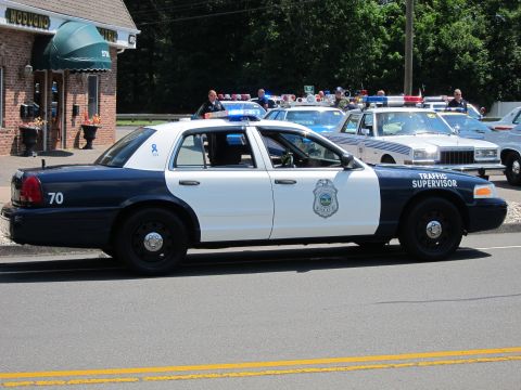 1991 Ford LTD Crown Victoria - blue-and-white Traffic Supervisor cruiser marked 70 on a street with police cars lined up behind.