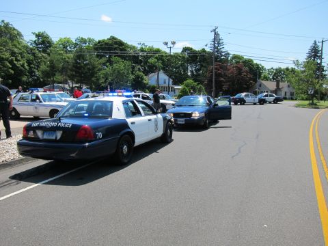 1991 Ford LTD Crown Victoria - East Hartford Police cruiser marked 70 and a black cruiser parked across a residential street.
