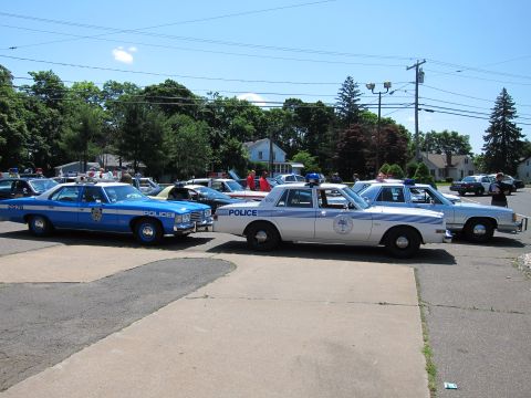 1991 Ford LTD Crown Victoria - Vintage blue and silver Police sedans parked side by side on pavement at an outdoor car show.