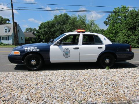 1991 Ford LTD Crown Victoria - Side profile of a black-and-white Traffic Supervisor police cruiser marked 70 on a gravel shoulder.