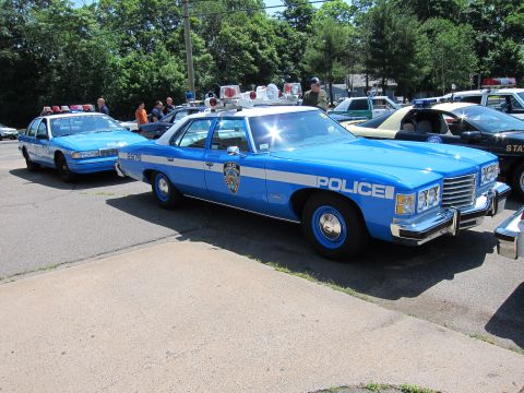 1991 Ford LTD Crown Victoria - blue Police sedan with NYPD-style markings parked among other cruisers at an outdoor car show.