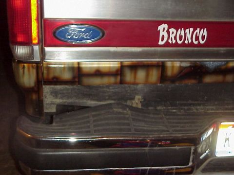 1989 Ford Bronco - The rear of a 1989 Ford Bronco shows the iconic 'Bronco' script and Ford emblem, with visible rust.