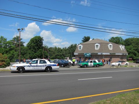 1991 Ford LTD Crown Victoria - white police traffic sedan and a green-and-white cruiser parked outside a brick building during a daytime gathering.