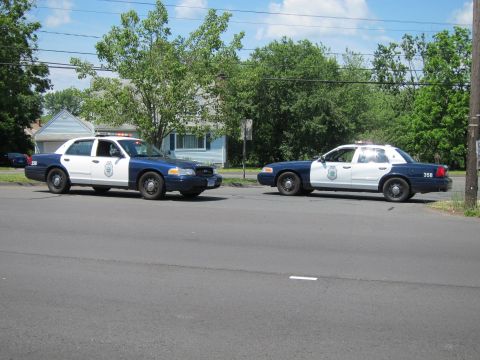 1991 Ford LTD Crown Victoria - Two blue-and-white police Crown Victorias parked in a residential street, one front-facing and one in profile marked 358.