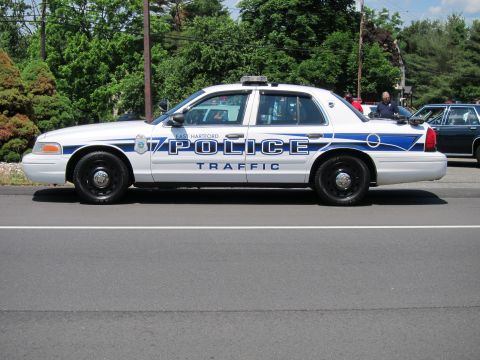 1991 Ford LTD Crown Victoria - side profile of an East Hartford Police Traffic Ford Crown Victoria sedan parked on a road with trees behind.