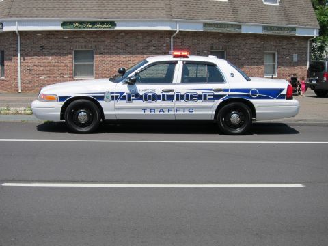 1991 Ford LTD Crown Victoria - side view of an East Hartford Police Traffic Crown Victoria with its roof light bar lit, parked by a brick building.