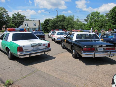 1991 Ford LTD Crown Victoria - green-and-white vintage Sheriff sedan beside a black-and-white Chevrolet Highway Patrol Caprice in a parking lot.