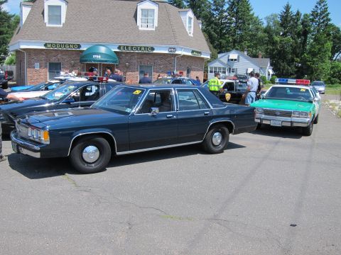 1991 Ford LTD Crown Victoria - dark blue Ford LTD Crown Victoria sedan parked beside a green-and-white police cruiser in a car-show lot.