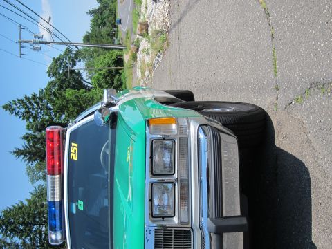 1991 Ford LTD Crown Victoria - close front view of a green-and-white vintage police car marked 251, its red-and-blue light bar atop the roof, parked roadside.