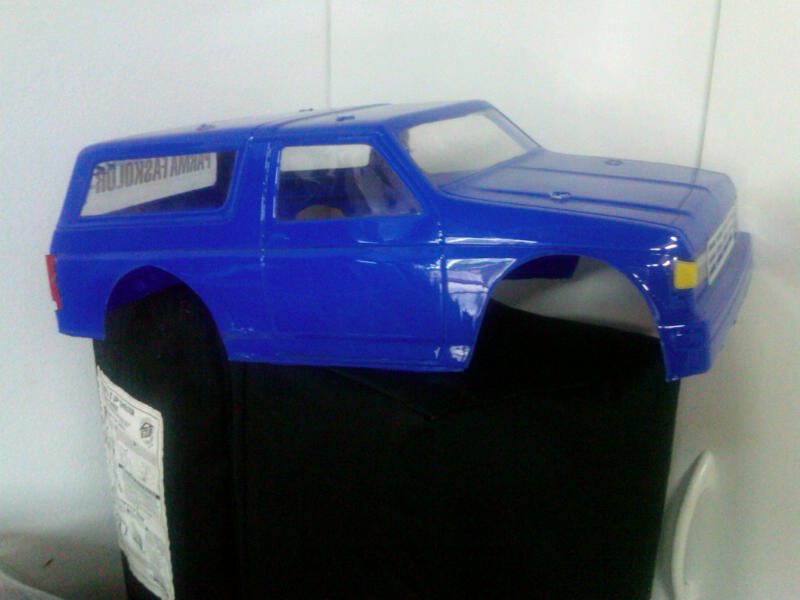 Blue plastic RC car body, looks like a Bronco, sitting on a black object