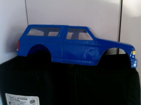 1986 Ford Bronco - A blue Ford Bronco body shell is shown from the side, resting on a black object.