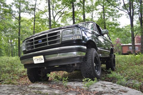 1995 Ford Bronco - 1995 Ford Bronco XLT in a wooded setting, showing its front quarter and lifted suspension.