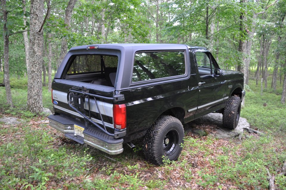 Black 1995 Ford Bronco parked on rocks in woods