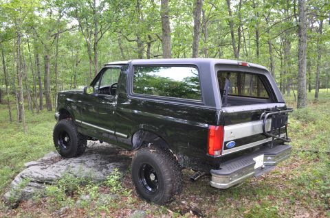 1995 Ford Bronco - Black 1995 Ford Bronco parked on rocks in a wooded area.