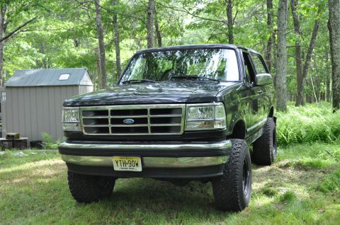 1995 Ford Bronco - 1995 Ford Bronco XLT shown from the front in a natural setting with a shed nearby.