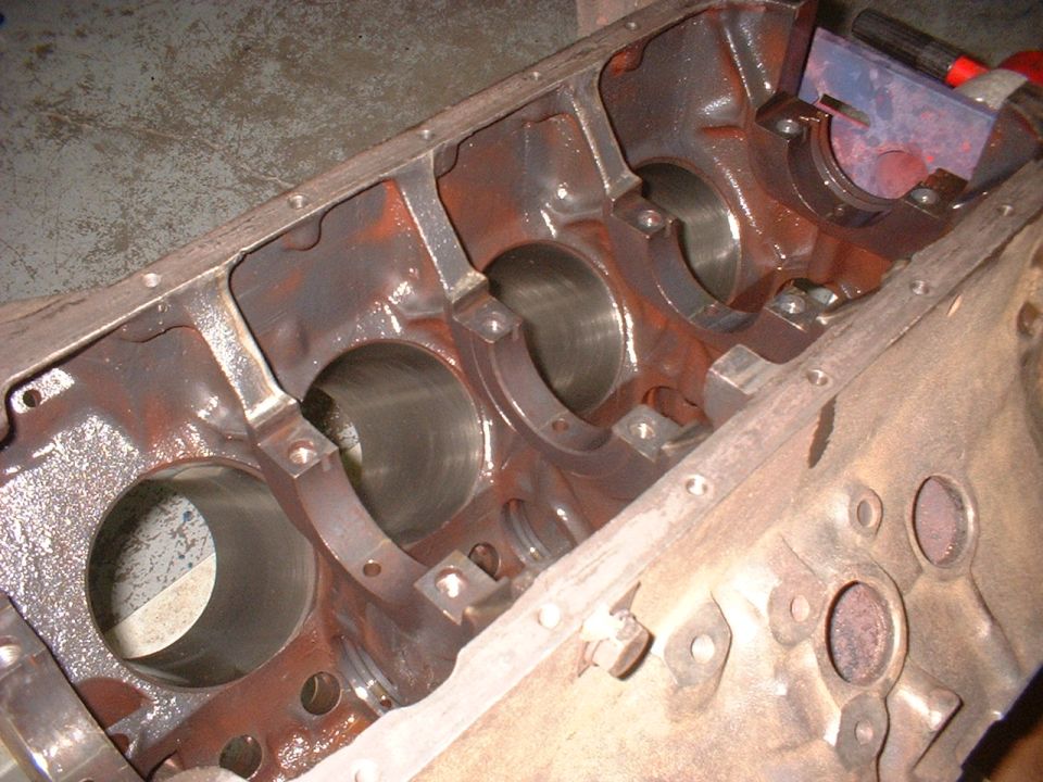Rusty engine block with cylinder bores visible, viewed from an angle