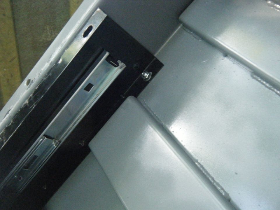 Metal drawer slide mechanism inside a gray compartment