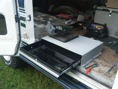 1988 Ford E350 - The interior of a van shows a slide-out drawer and various equipment, including a hitch receiver and tools.