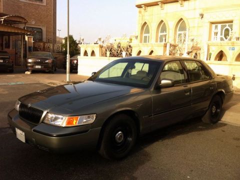 2001 Mercury Grand Marquis - A dark gray 2001 Mercury Grand Marquis is parked on a street in front of a building.