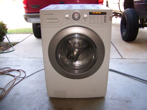 2000 Jeep Wrangler - A washing machine is positioned in front of two vehicles, a red pickup and a lifted truck.