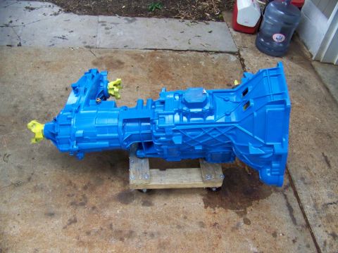 1985 Ford Bronco - A bright blue transmission, likely a manual gearbox, is mounted on a wooden dolly with wheels.