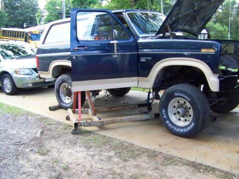 1985 Ford Bronco - Ford Bronco undergoing maintenance with its hood up and door open.