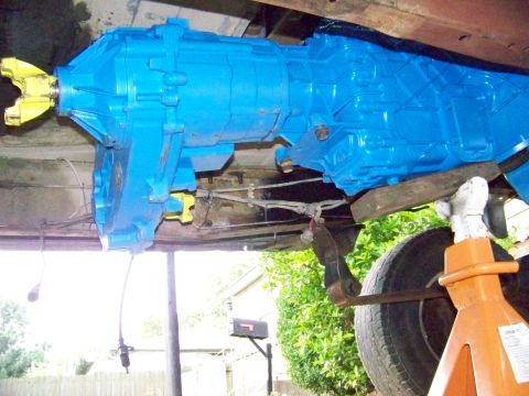 1985 Ford Bronco - Underside view of a vehicle's transmission, painted bright blue and supported by orange jack stands.
