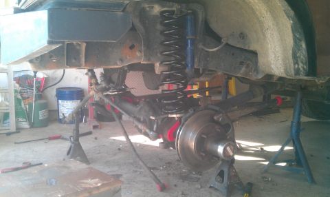1987 Ford Bronco - Vehicle suspension components, including springs and shocks, are visible while the vehicle is supported by jack stands.