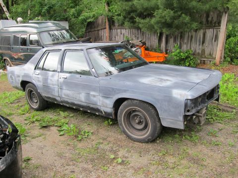 1991 Ford LTD Crown Victoria - A primer-coated Ford Crown Victoria sits in a yard next to a van, awaiting restoration.