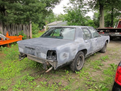 1991 Ford LTD Crown Victoria - A gray sedan in primer, viewed from the rear, with missing taillights and bumper components.