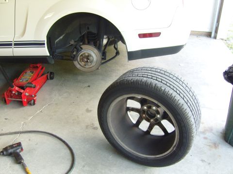2007 Ford Mustang - Rear wheel removed from a 2007 Ford Mustang, with a floor jack and impact wrench nearby.