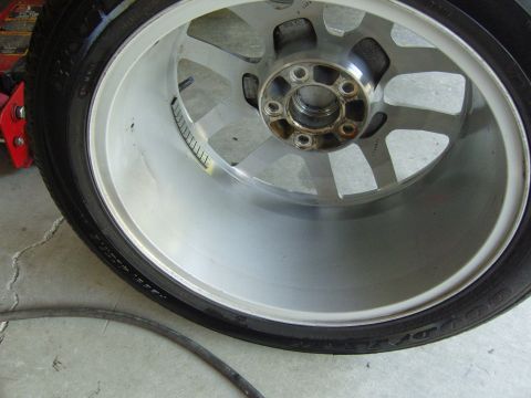 2007 Ford Mustang - A close-up view of a car's alloy wheel and tire, with a red jack visible in the background.