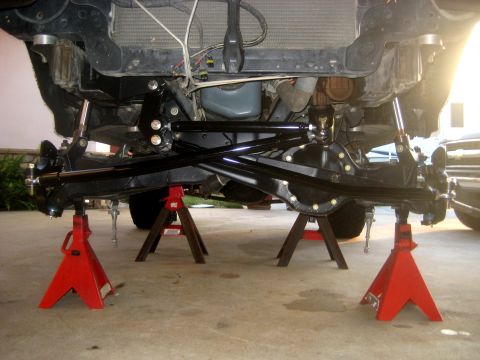 1996 Ford Bronco - Undercarriage of a vehicle on jack stands, showing suspension and drivetrain components.