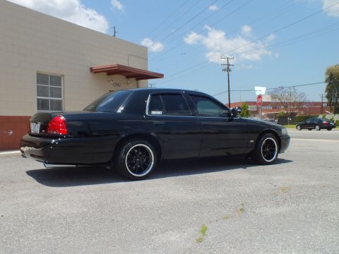 2003 Ford Crown Victoria - Right rear 3/4; lowered black sedan, tinted glass, building door 12942 behind