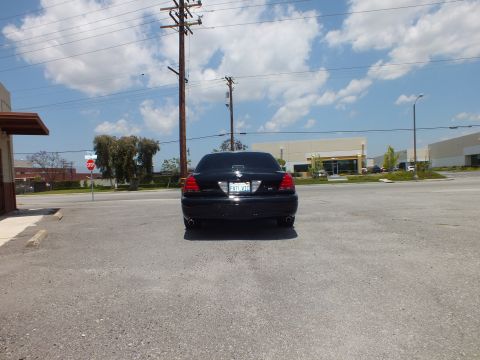 2003 Ford Crown Victoria - Straight rear view from distance; blacked-out sedan, California plate, power lines above